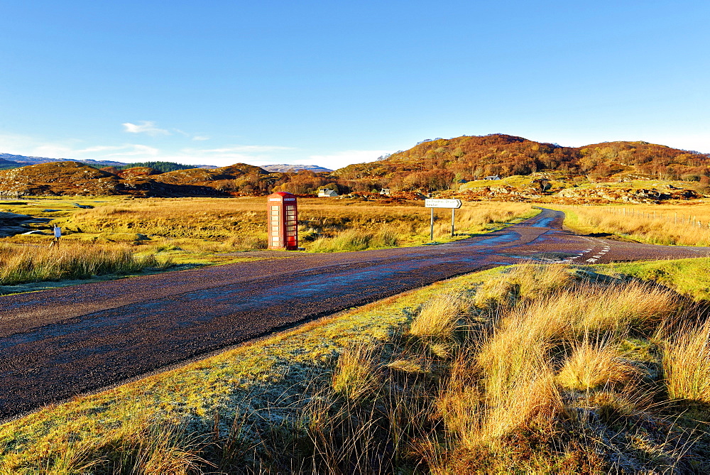 An autumn view of a red telephone box at the side of a quiet road in the remote Ardnamurchan moors of the Scottish Highlands, Scotland, United Kingdom, Europe