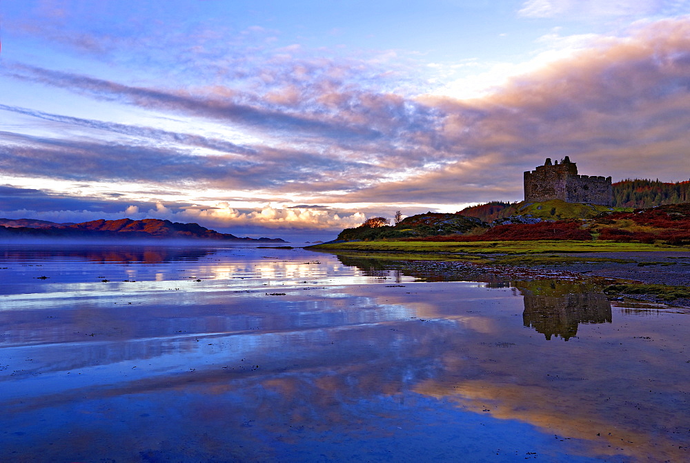 Early morning view of Castle Tioram and Loch Moidart as dawn breaks in a warm colorful sky to form attractive reflections, Highlands, Scotland, United Kingdom, Europe