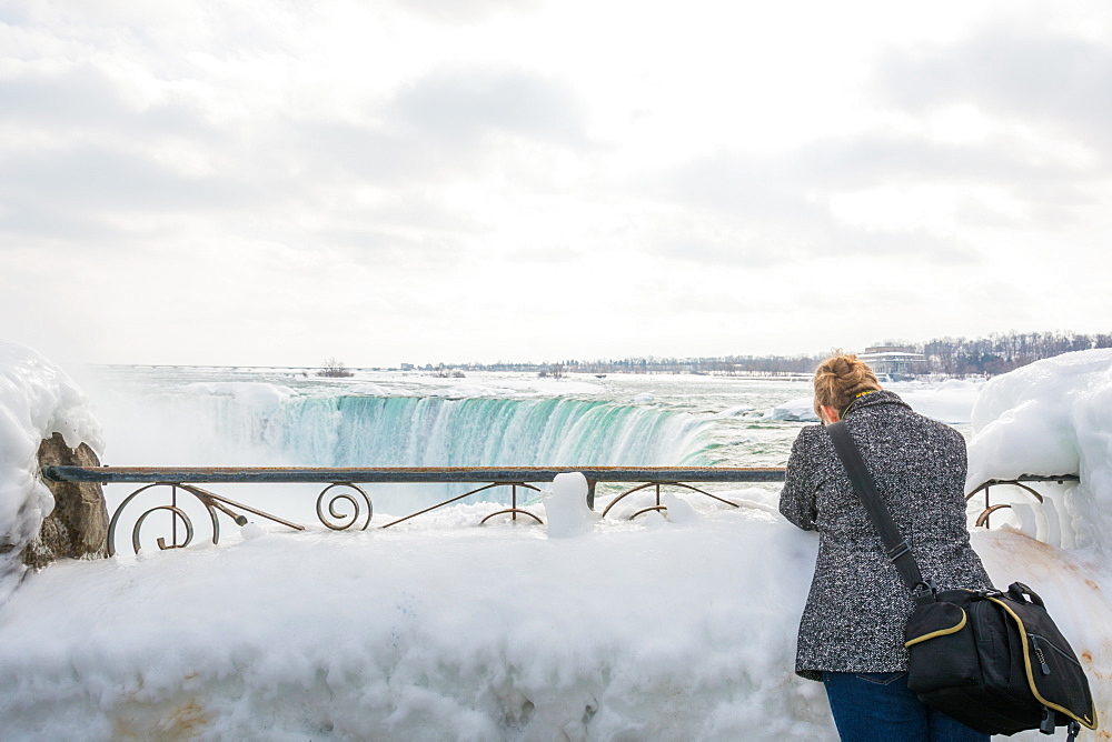 A lady takes a photograph of the Frozen Niagara Falls in March, Ontario, Canada, North America