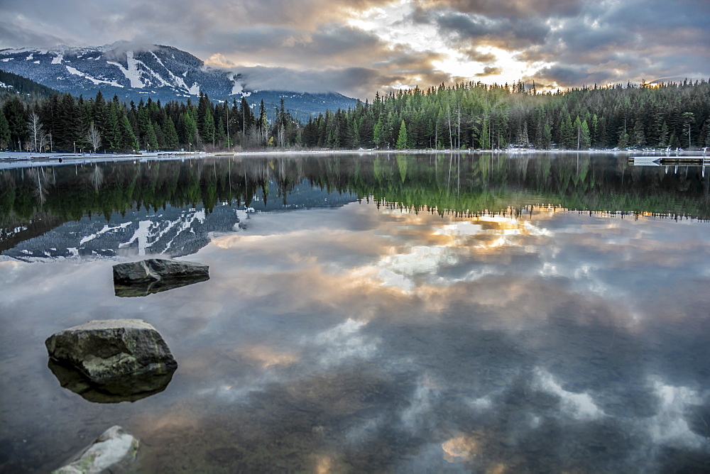 Lost Lake, so still it gives a perfect reflection of the sunset, ski hill and surrounding forest, Whistler, British Columbia, Canada, North America