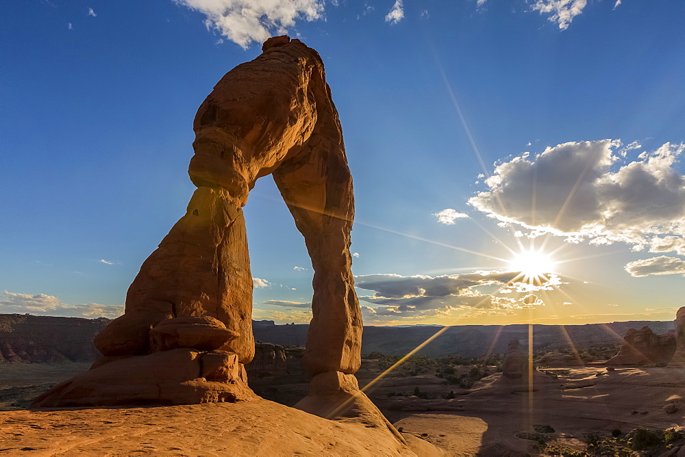 Delicate Arch with sun and clouds at golden hour, Arches National Park, Moab, Grand County, Utah, United States of America, North America