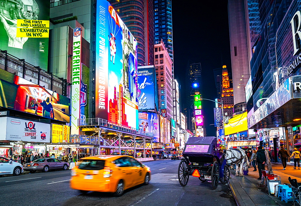 The bright lights of New York City's Times Square with an iconic yellow cab passing through, New York, United States of America, North America