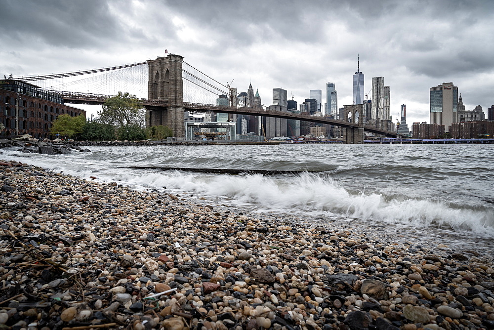 A pebble beach on the East River in Brooklyn looking towards the Brooklyn Bridge and Lower Manhattan, New York, United States of America, North America