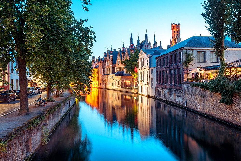 A tranquil canal scene in Bruges, with the spires of the Stadhuis (Town Hall) in the distance, Bruges, Belgium, Europe