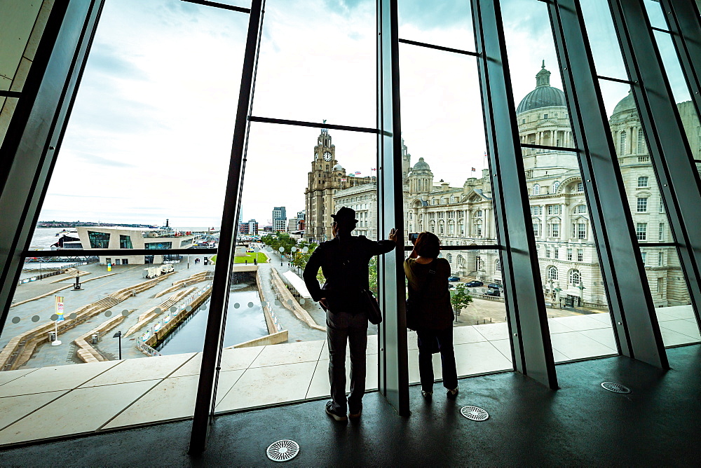 A couple look out over Pier Head and the Liver Building from the large windows at the Museum of Liverpool, Liverpool, Merseyside, England, United Kingdom, Europe