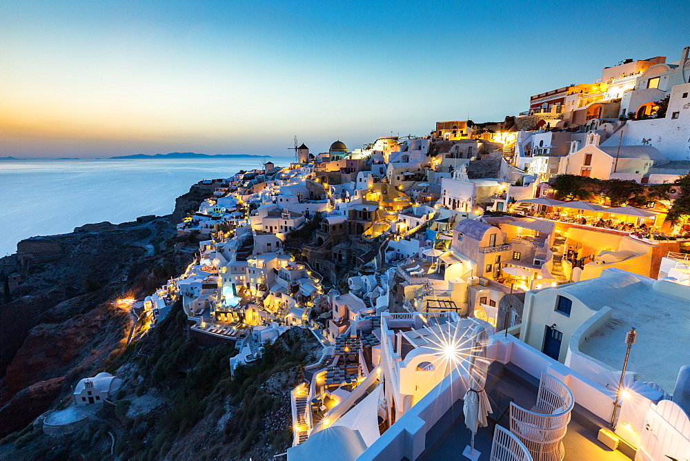 Sunset over the white stone buildings and windmills of Oia on the tip of Santorini's caldera, Santorini, Cyclades, Greek Islands, Greece, Europe