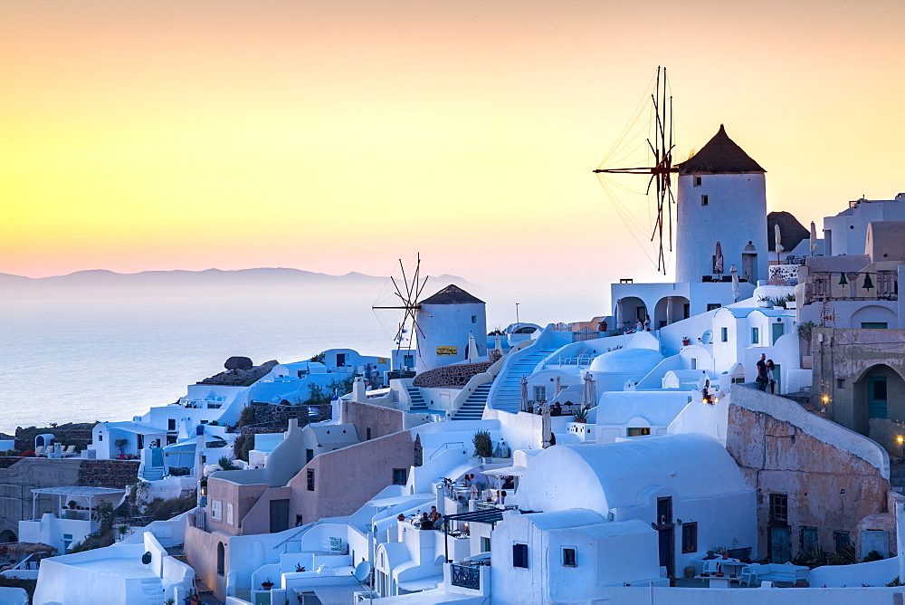 Sunset over the white stone buildings and windmills of Oia on the tip of Santorini's caldera, Santorini, Cyclades, Greek Islands, Greece, Europe