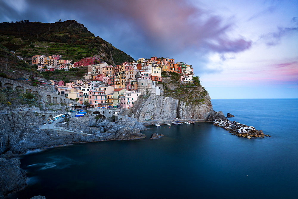 The clouds over Manarola light up with the colours of sunset during a long exposure, Manarola, Cinque Terre, UNESCO World Heritage Site, Liguria, Italy, Europe