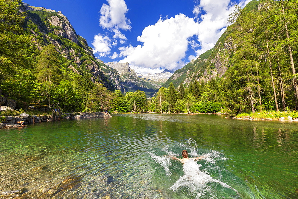 A boy swims in a clear alpine lake, Val di Mello (Mello Valley), Valmasino, Valtellina, Lombardy, Italy, Europe