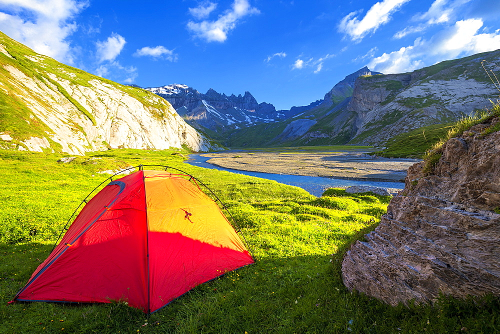 The sun illuminates a red tent, Unterer Segnesboden, Flims, District of Imboden, Canton of Grisons (Graubunden), Switzerland, Europe