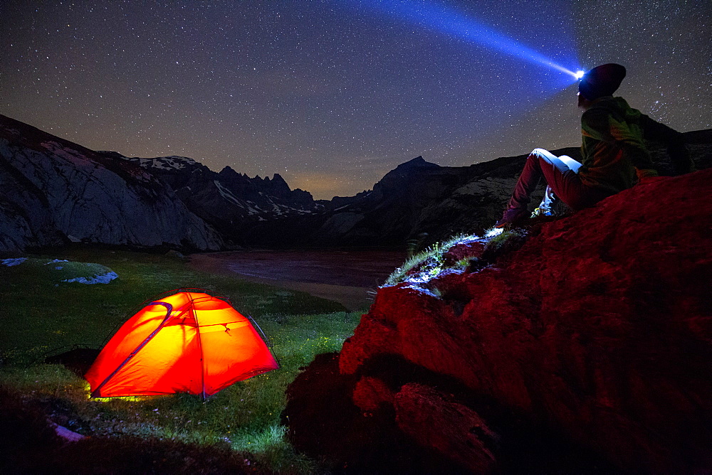 A person looks at stars near his red tent, Unterer Segnesboden, Flims, District of Imboden, Canton of Grisons (Graubunden), Switzerland, Europe