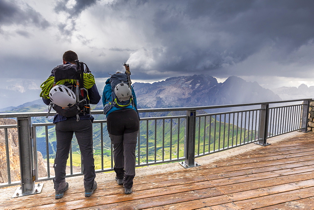 Two mountain climbers watch the storm above Marmolada, Pordoi Pass, Fassa Valley, Trentino, Dolomites, Italy, Europe