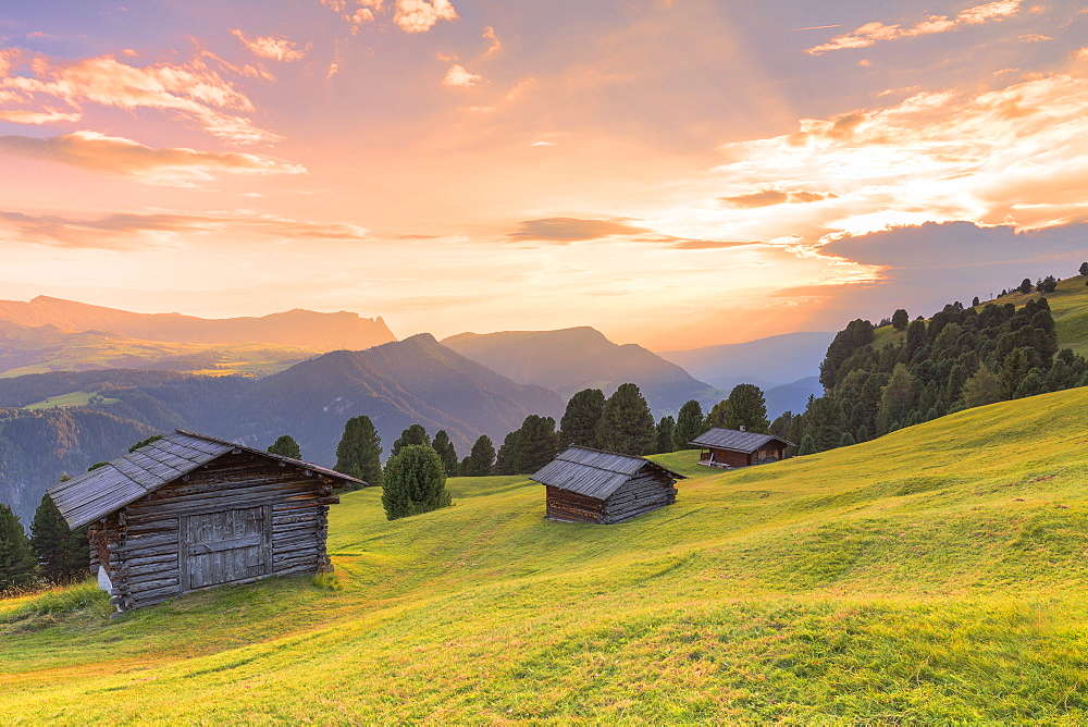 Sunset above traditional huts in the pasture, Gardena Valley, South Tyrol, Dolomites, Italy, Europe