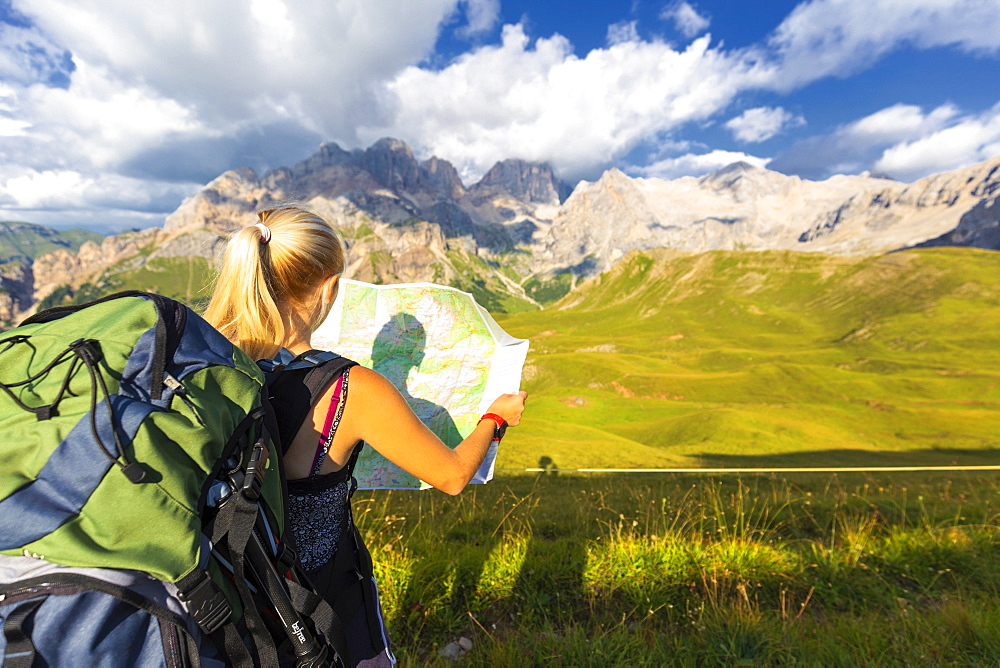 Hiker reading map with Marmolada in the background, San Nicolo Pass, Fassa Valley, Trentino, Dolomites, Italy, Europe