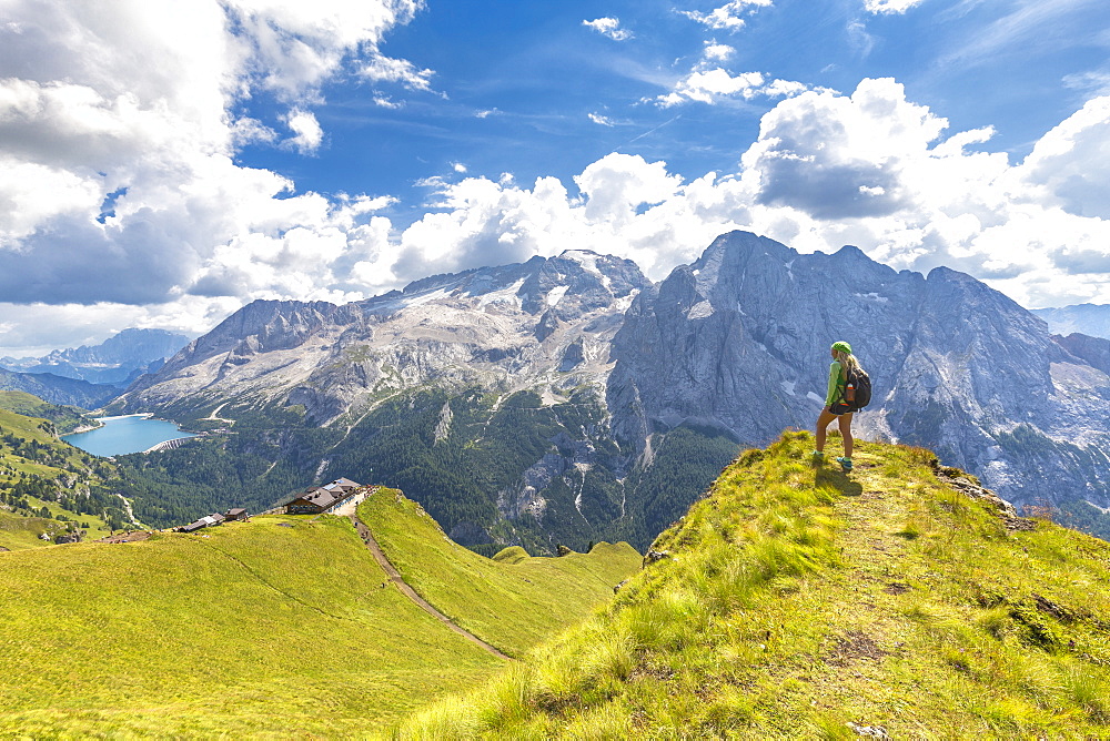 Hiker looks towards Viel del Pan Refuge with Marmolada in the background, Pordoi Pass, Fassa Valley, Trentino, Dolomites, Italy, Europe