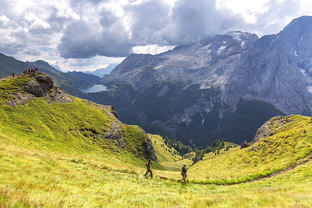 Hikers walk on Viel del Pan Path near Pordoi Pass, Fassa Valley, Trentino, Dolomites, Italy, Europe