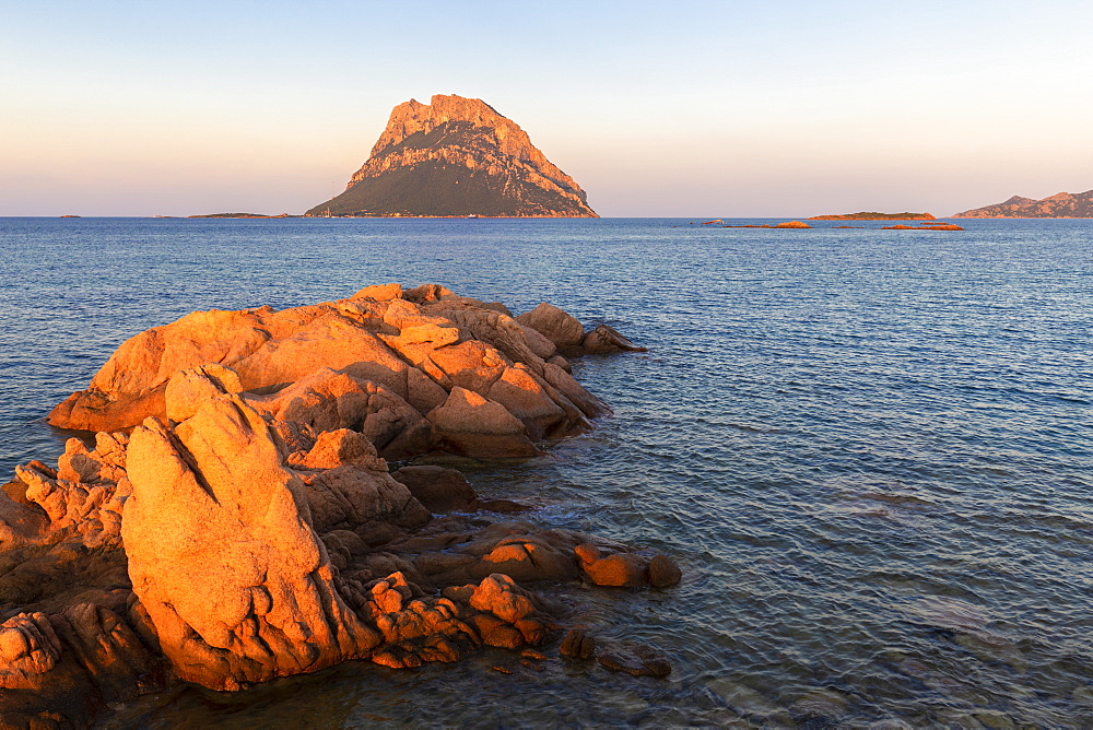 Sun illuminates rocks with Tavolara Island in the background at sunset, Loiri Porto San Paolo, Olbia Tempio province, Sardinia, Italy, Mediterranean, Europe