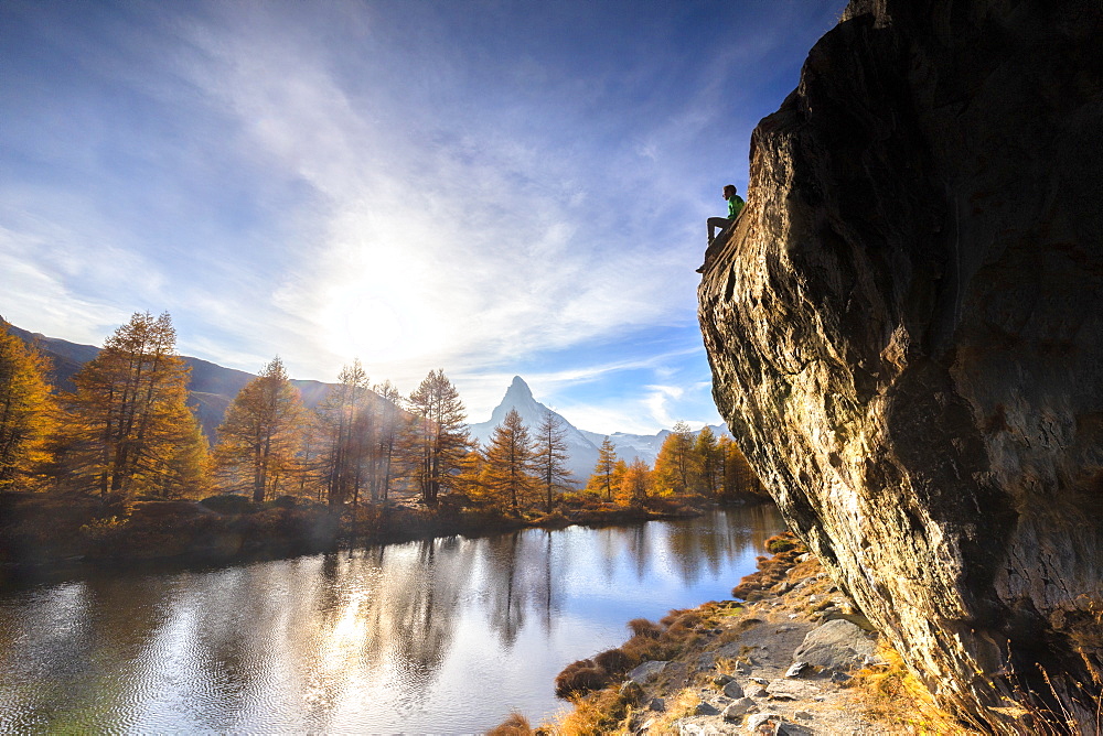 Man on rock above Grindjisee Lake during autumn in Zermatt, Switzerland, Europe