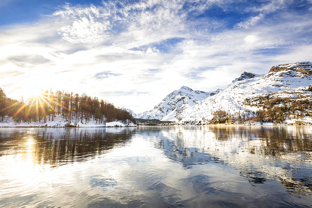 The sun illuminates the icy surfaces of Lake Sils, Engadine Valley, Graubunden, Swiss Alps, Switzerland, Europe