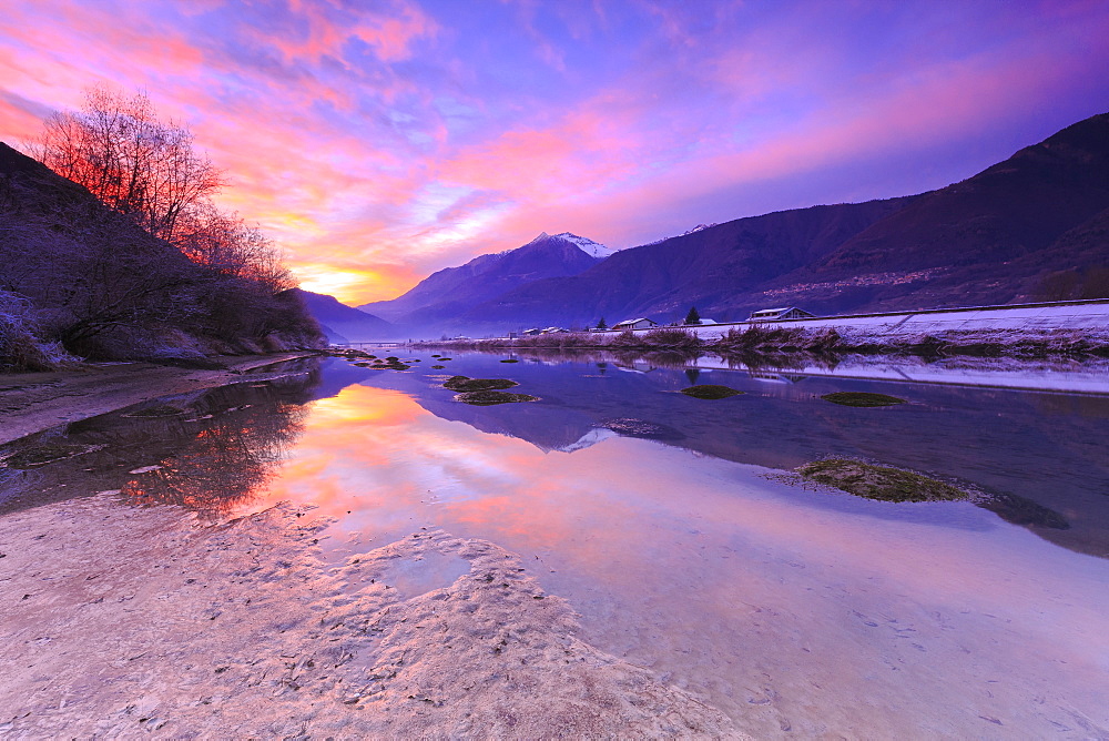 The colors of sunset are reflected in the Adda River, Valtellina, Lombardy, Italy, Europe