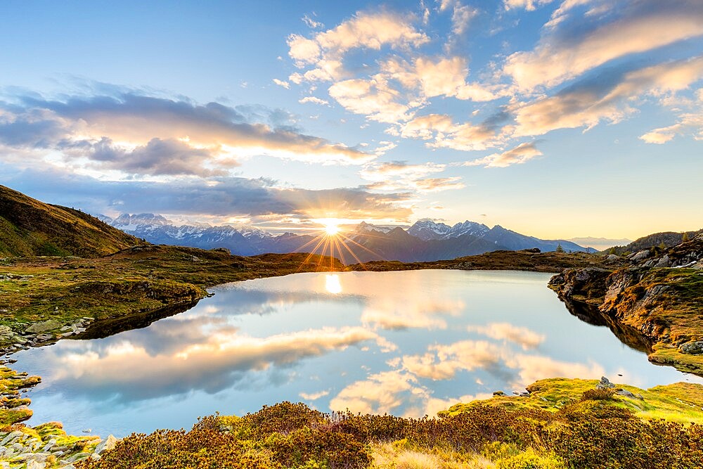 The sun and clouds reflected in the Arcoglio Lake at sunrise, Valmalenco, Valtellina, Lombardy, Italy, Europe