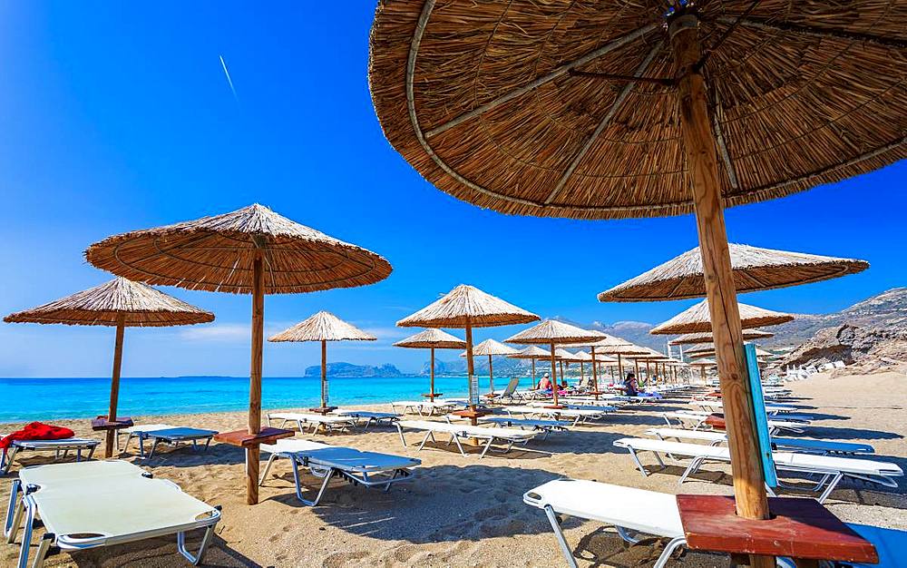 Umbrellas on the beach and emerald seas at Falassarna beach in Western Crete, Greek Islands, Greece, Europe