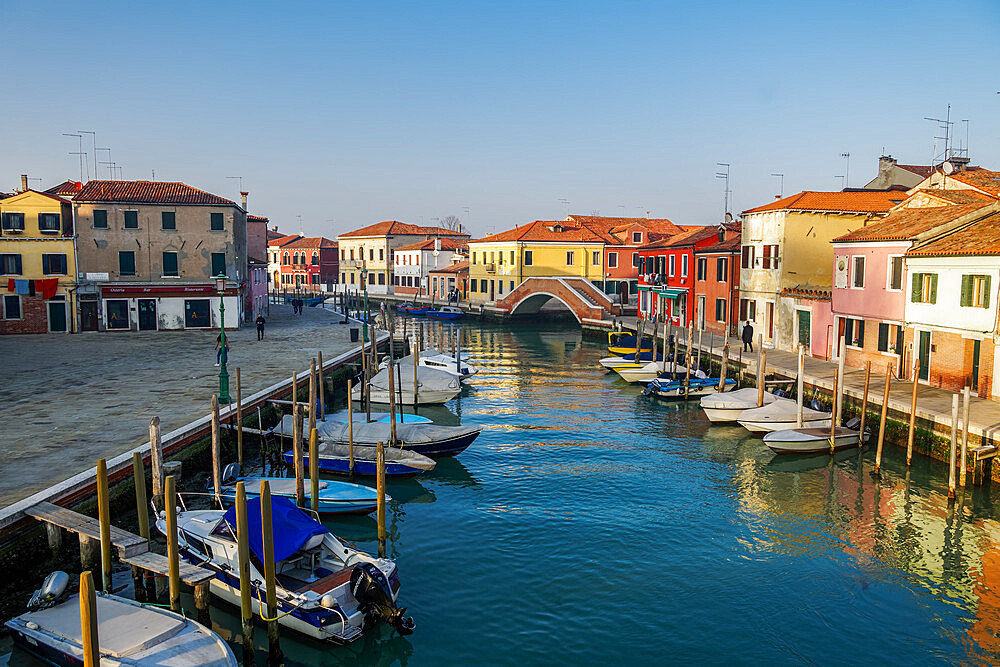 View of Ponte San Martino stone bridge over canal with colorful buildings and moored boats on wooden wharf pilings, Venice, UNESCO World Heritage Site, Veneto, Italy, Europe