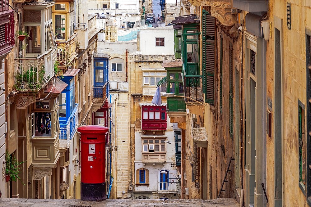 Typical street scene of alley with traditional homes, colorful balconies and red post box, Valletta, Malta, Europe