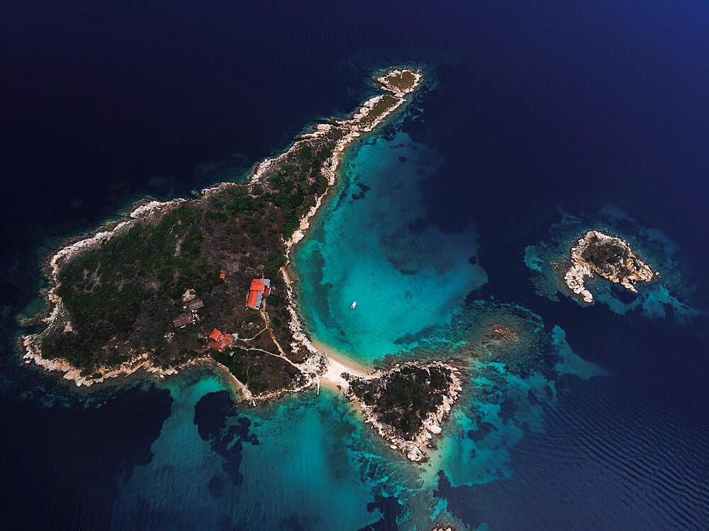 Drone above small island with house, green vegetation and rocky coastline in the Mediterranean at Chalkidiki peninsula, Greece, Europe