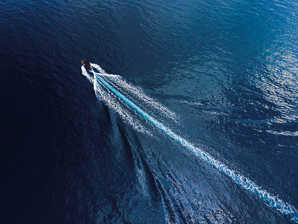 Drone view of small boat sailing in calm blue waters, Greece, Europe