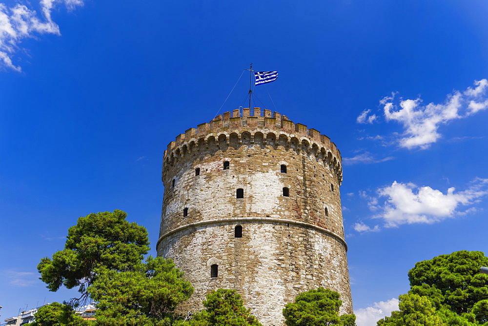 View of the city's landmark The White Tower, with Greek flag waving on top, Thessaloniki, Greece, Europe