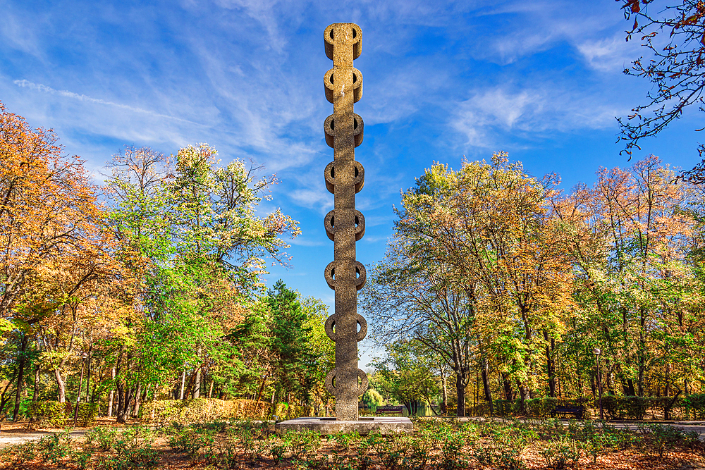 Coloana monument (Coloana Comemorativa) surrounded by greenery at a park next to the Free Press square under a blue sky, Bucharest, Romania, Europe