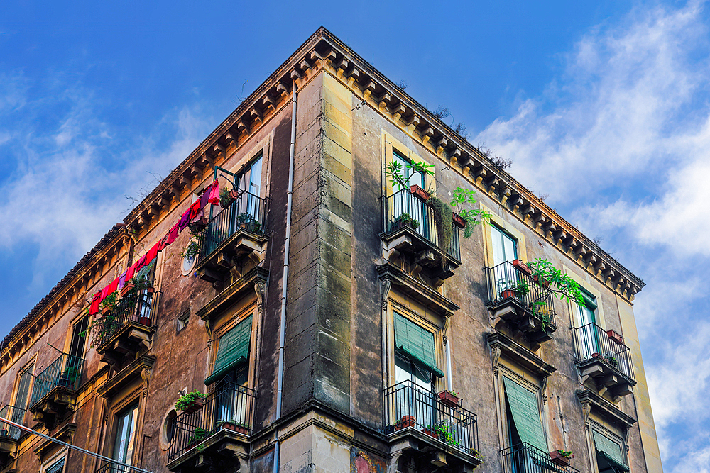 Traditional architecture of house with iron balconies with flowers and a slightly decayed facade, Catania, Sicily, Italy, Mediterranean, Europe