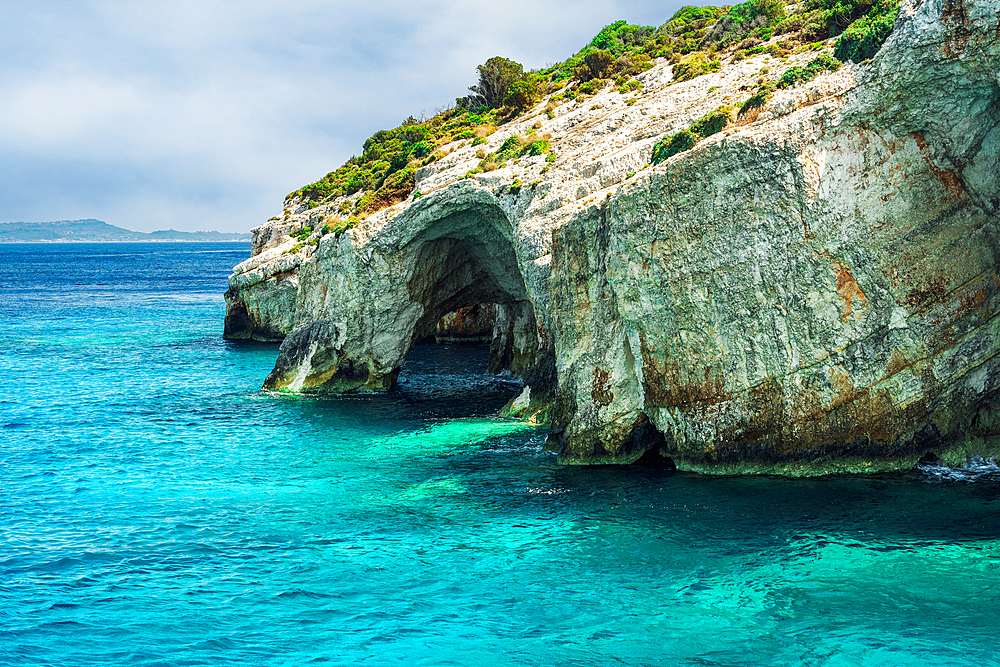 Natural cave formation on a rocky hill with green plantation stretching to the sea, Zakynthos, Ionian Islands, Greek Islands, Greece, Europe