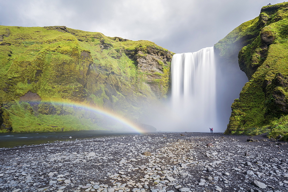 Double rainbow and tourists with hands in the air at Skogafoss waterfall in South Iceland, Polar Regions