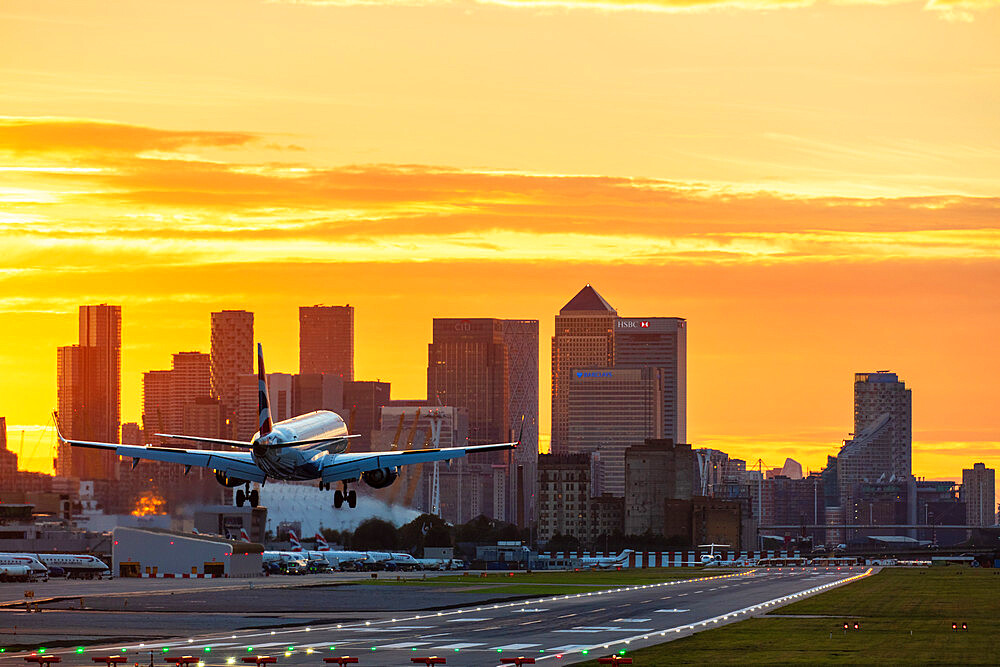 Aircraft landing at London City Airport at sunset, with Canary Wharf and O2 Arena in background, London, England, United Kingdom, Europe