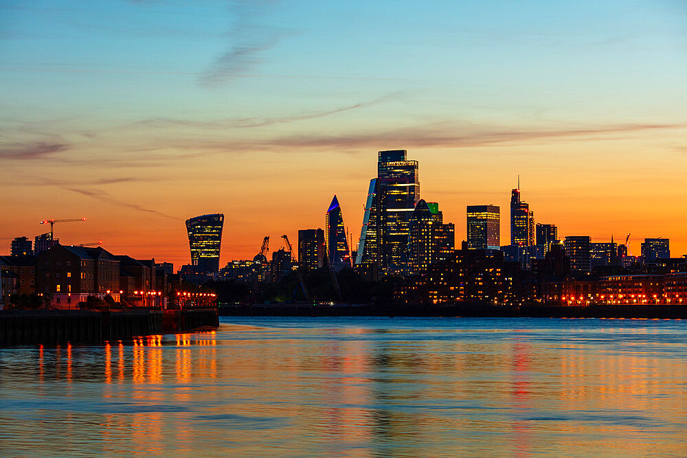 The City of London skyline at sunset reflecting in River Thames, London, England, United Kingdom, Europe