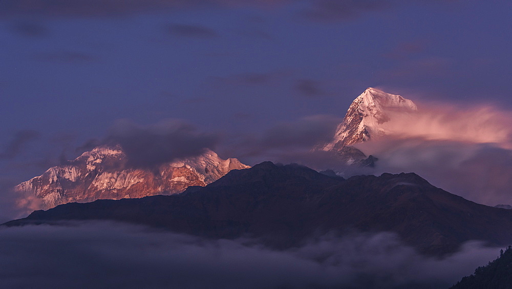 The clouds gradually clearing to reveal the evening light on Annapurna South, viewed from Poon Hill, Himalayas, Nepal, Asia