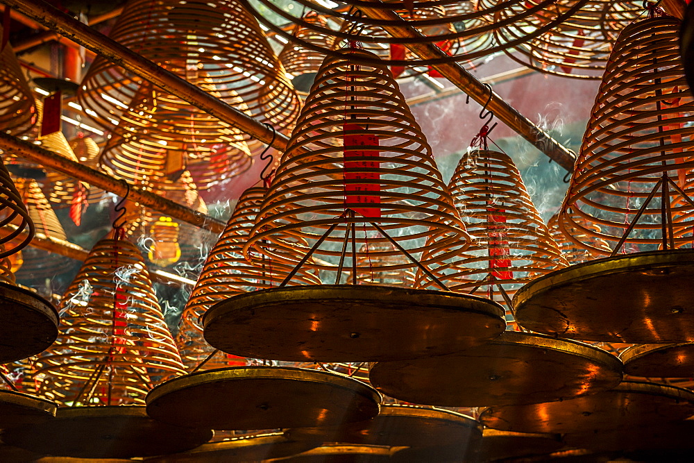 Beams of light streaming into Man Mo Temple past the large incense coils hanging from the ceiling of the Temple, Hong Kong, China, Asia