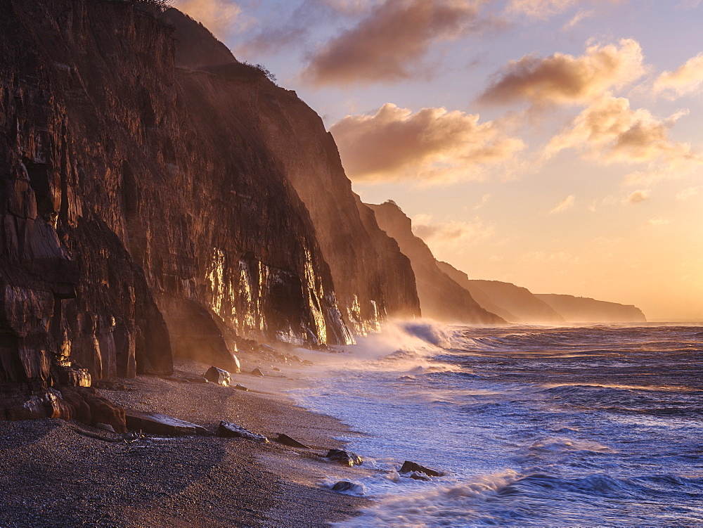 Spray from a storm blows up the cliffs at dawn in the seaside town of Sidmouth, Devon, England, United Kingdom, Europe