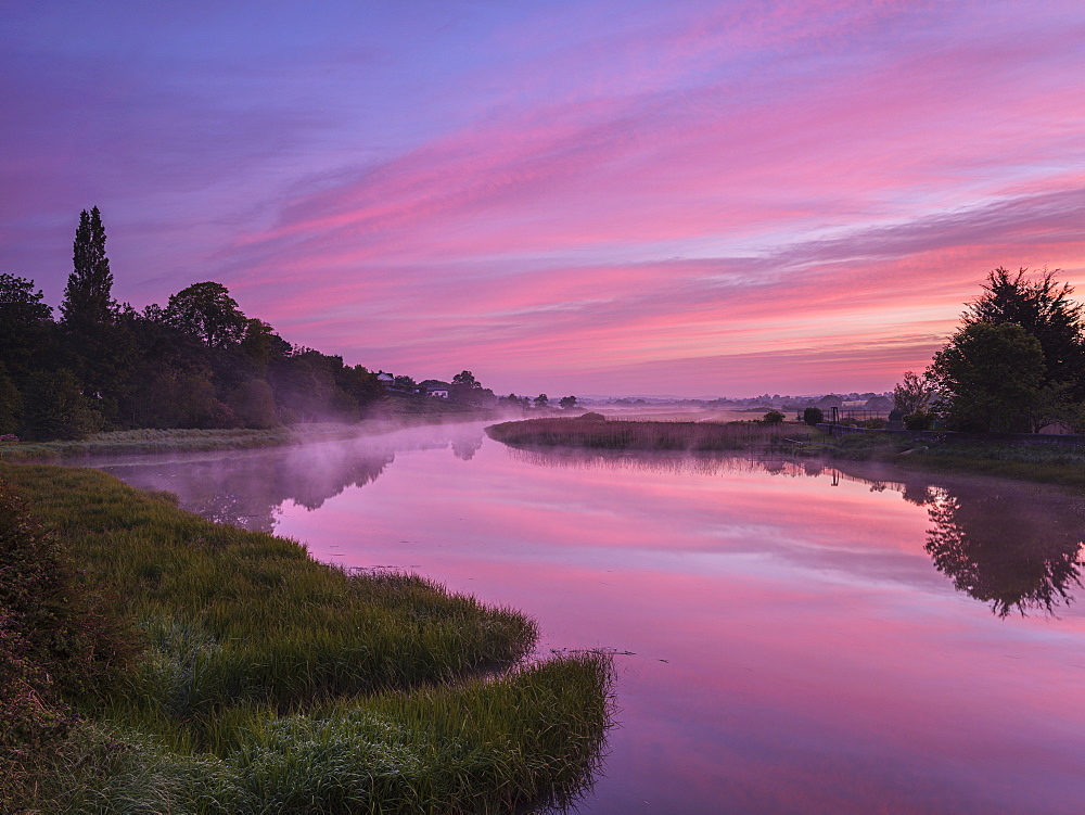 Dawn sky and rising mist from a mirror calm River Clyst at Topsham, Devon, England, United Kingdom, Europe