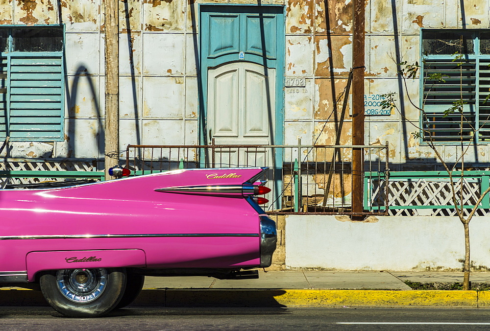 A classic American car driving past an old building in Varadero, Cuba, West Indies, Caribbean, Central America