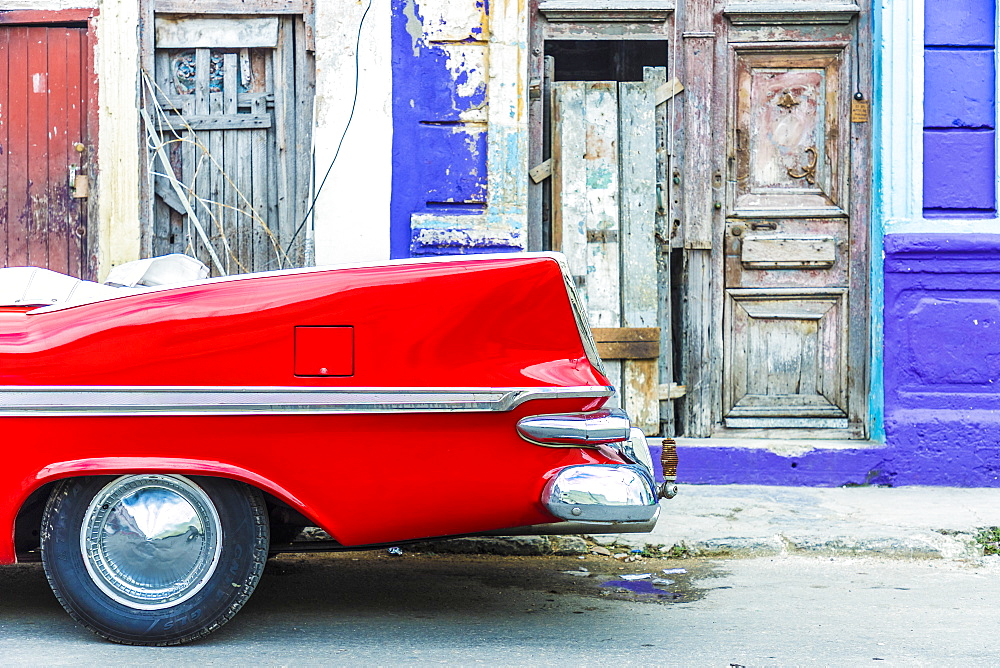 A red vintage car parked against colourful local architecture in Havana, Cuba, West Indies, Caribbean, Central America