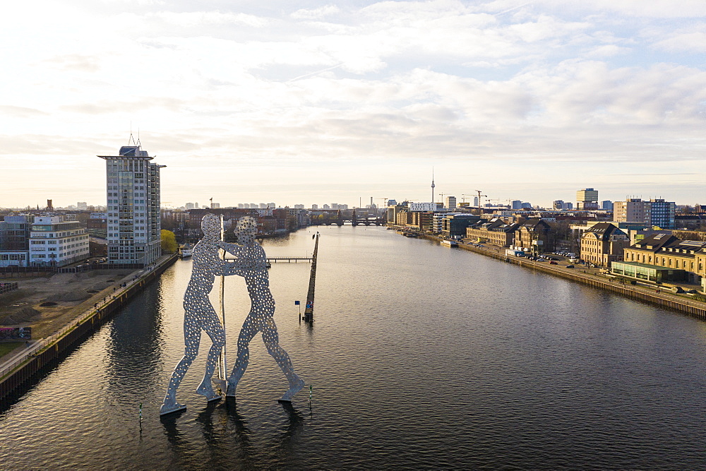 View of the Molecule Man statue in Treptow with Spree River and Berlin skyline in the background, Berlin, Germany, Europe