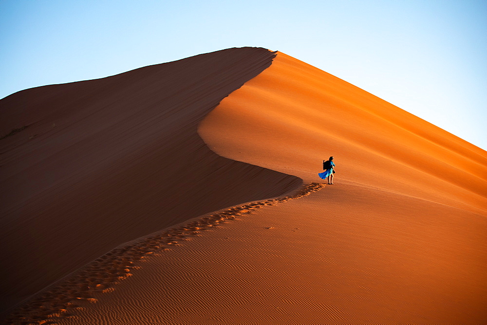 Shot of model Climbing Dune 13 with photography gear, Sossusvlei, Namibia, Africa