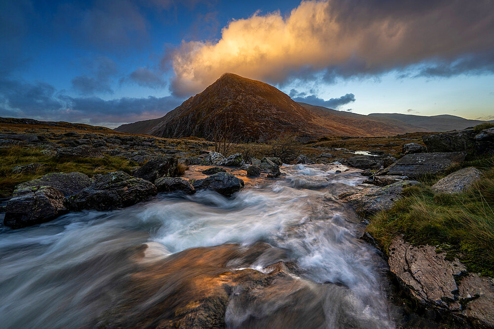 Water cascading down a fall towards Llyn Dinas backed with mountain range, Snowdonia, Wales