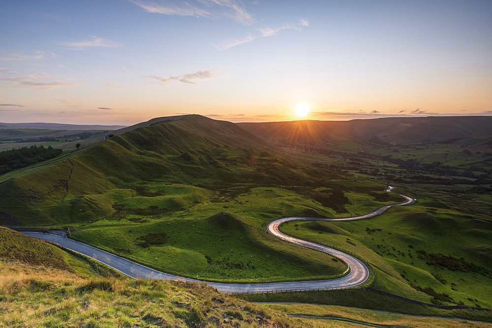 Long and winding rural road leading through green hills in the Peak District, with Rushup Edge, Peak District National Park, Derbyshire, England, United Kingdom, Europe