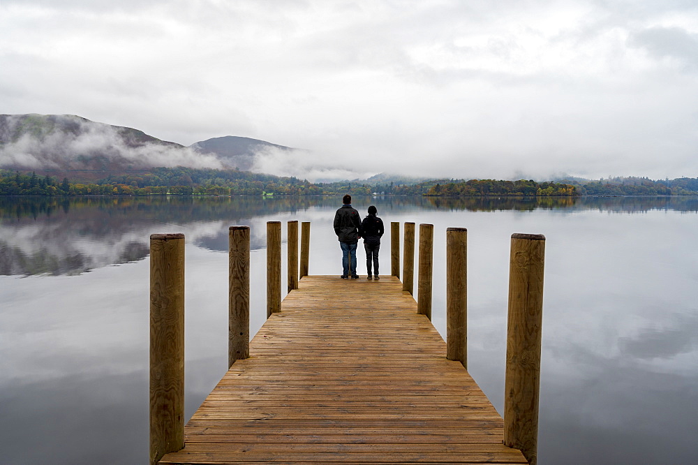 A couple standing on Ashness Pier Landing Jetty, Derwentwater, Keswick, Lake District National Park, UNESCO World Heritage Site, Cumbria, England, United Kingdom, Europe