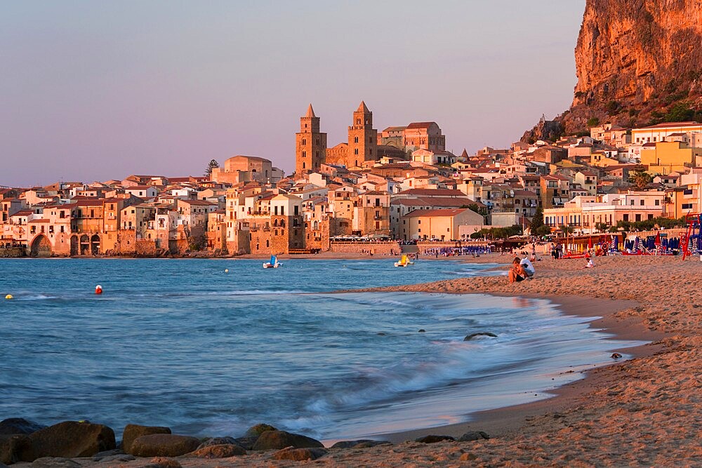 View from beach along water's edge to the town and UNESCO World Heritage Site listed Arab-Norman cathedral, sunset, Cefalu, Palermo, Sicily, Italy, Mediterranean, Europe