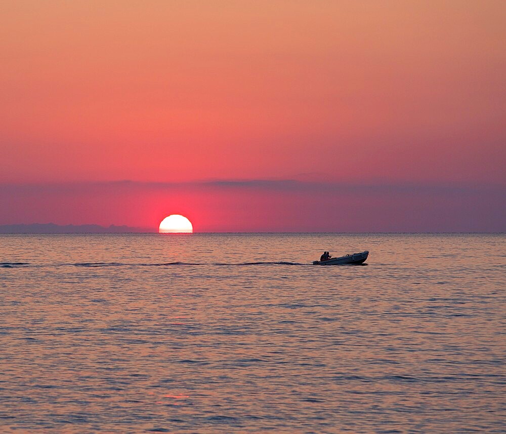 View across the Tyrrhenian Sea at sunrise, small boat crossing Calura Bay, Cefalu, Palermo, Sicily, Italy, Mediterranean, Europe